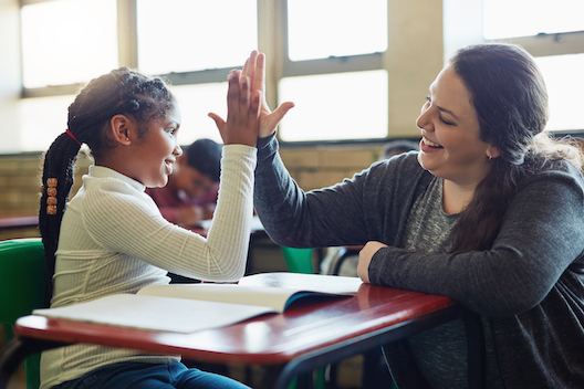 Student and teacher give high-five with hands.